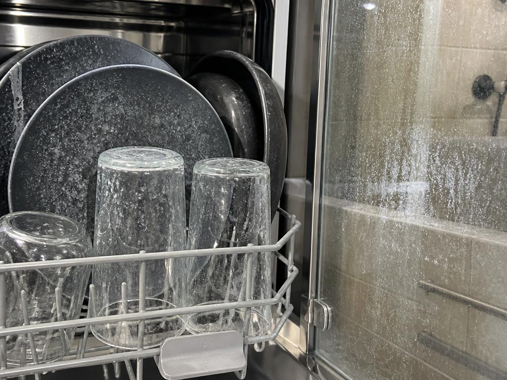 Hard water spots on dishwasher glassware and soap scum on a glass shower door